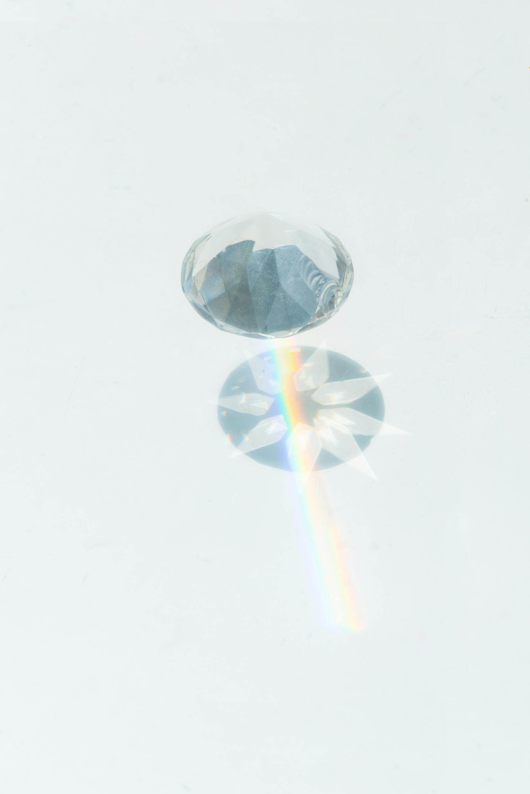A sparkling diamond casting vibrant rainbow reflections on a smooth white background.
