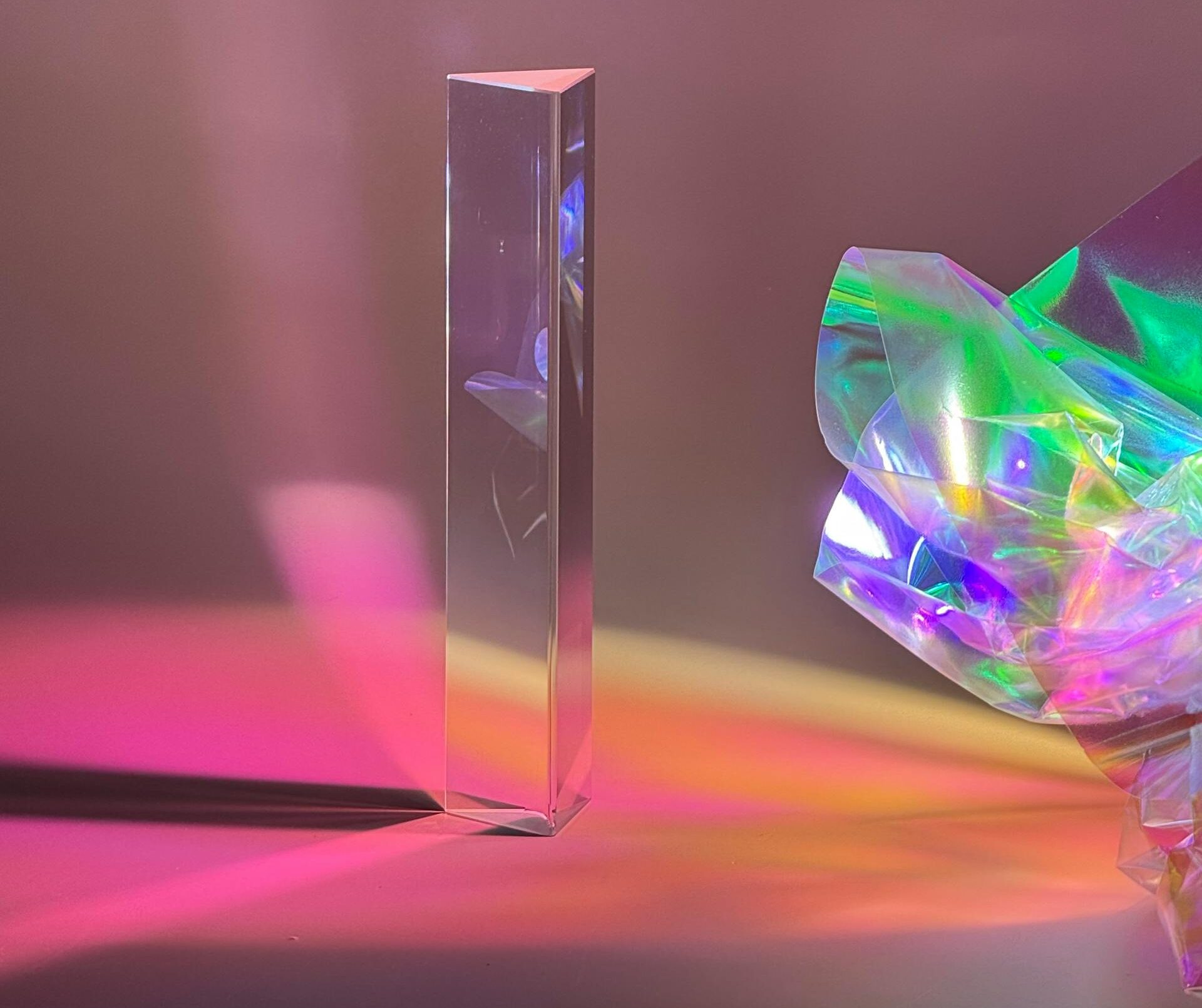 A tall prism casting colorful reflections on a surface with holographic film.