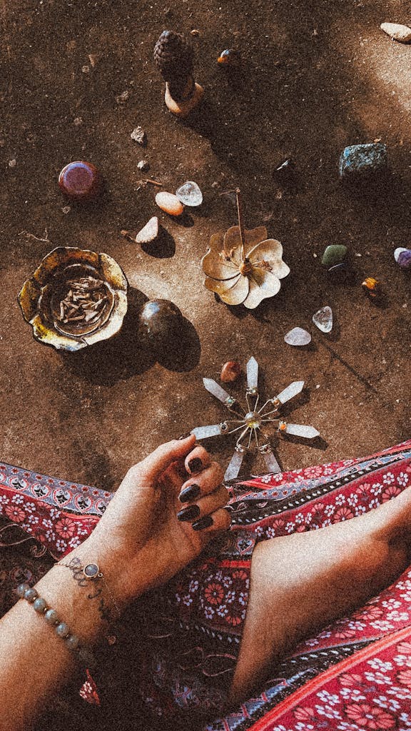 A woman's hand in a spiritual ritual with crystals, incense, and natural elements.